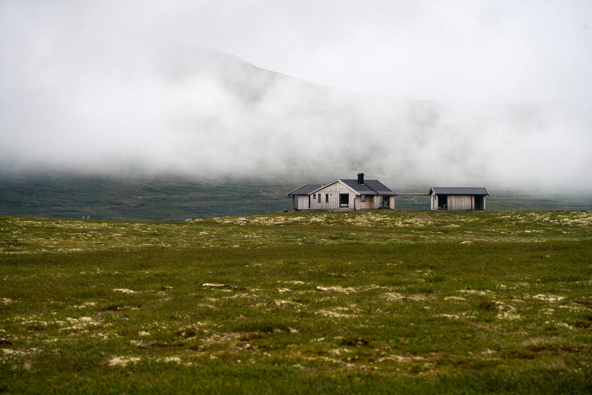 Hus på slette foran skylagt fjell